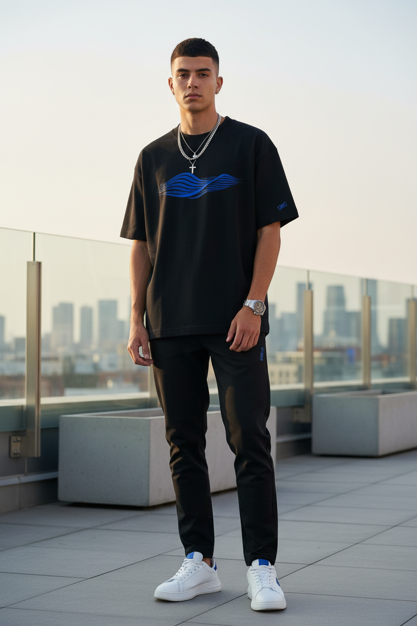 Front-facing model in clean urban setting wearing blue wave t-shirt